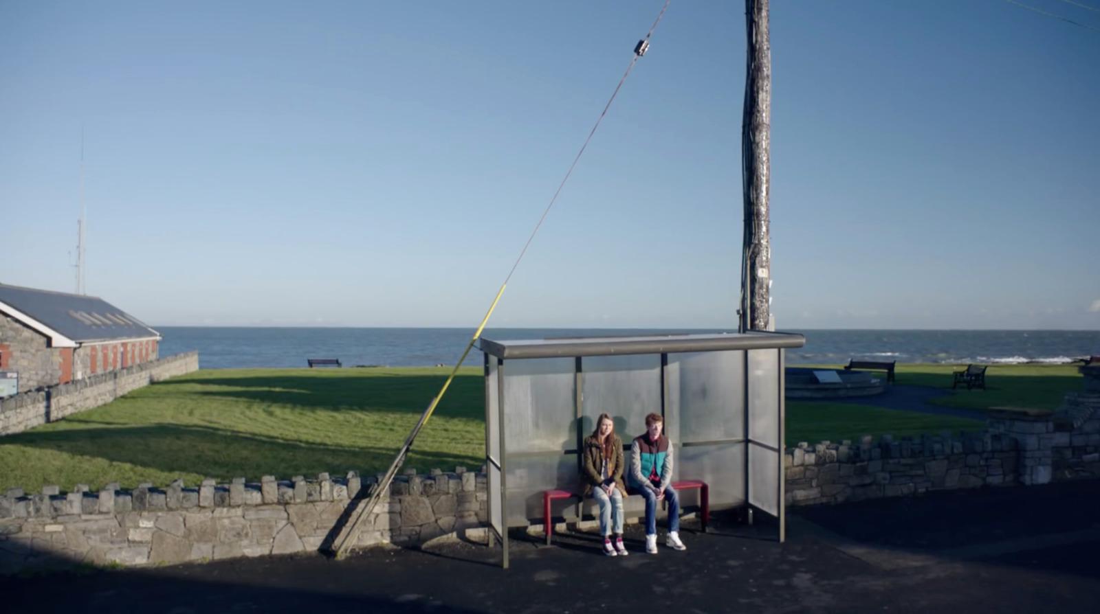 a couple of people sitting on a bench next to a body of water