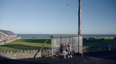 a couple of people sitting on a bench next to a body of water