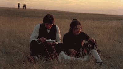 two people sitting in a field of tall grass