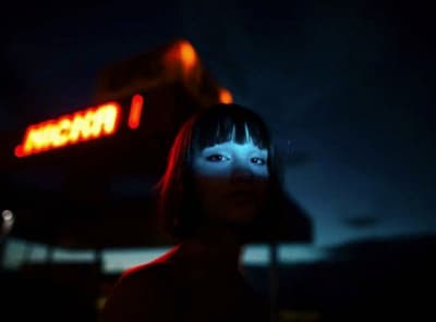 a woman standing in front of a neon sign