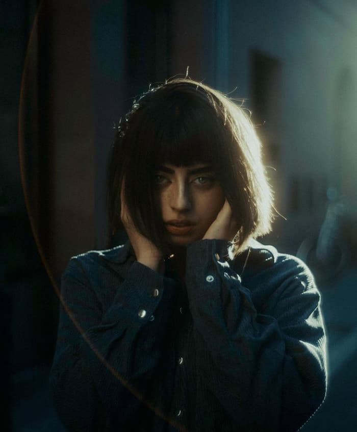 a woman in a dark room holding her hand to her face