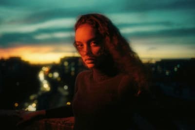 a woman with long hair standing in front of a cityscape