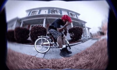 a man with red hair riding a bike in front of a house