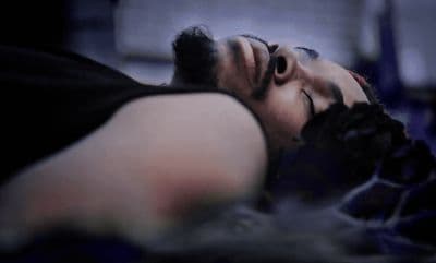 a man sleeping on a bed with his eyes closed