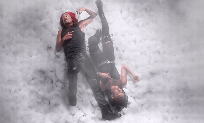 a couple of people laying on top of a pile of snow
