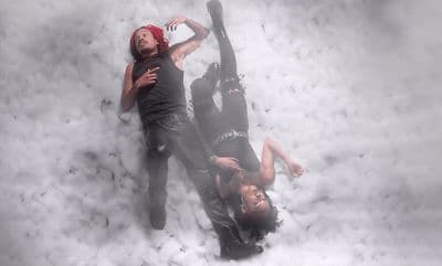 a couple of people laying on top of a pile of snow
