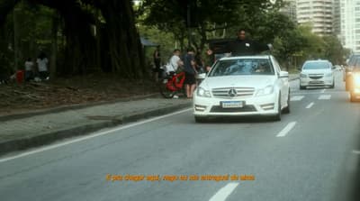 a white car driving down a street next to tall buildings