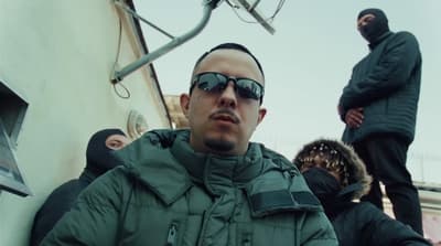 a man in a green jacket wearing sunglasses