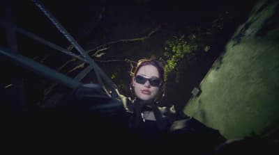 a woman wearing sunglasses standing on a stairway