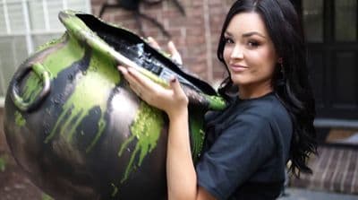 a woman holding a large green and black vase