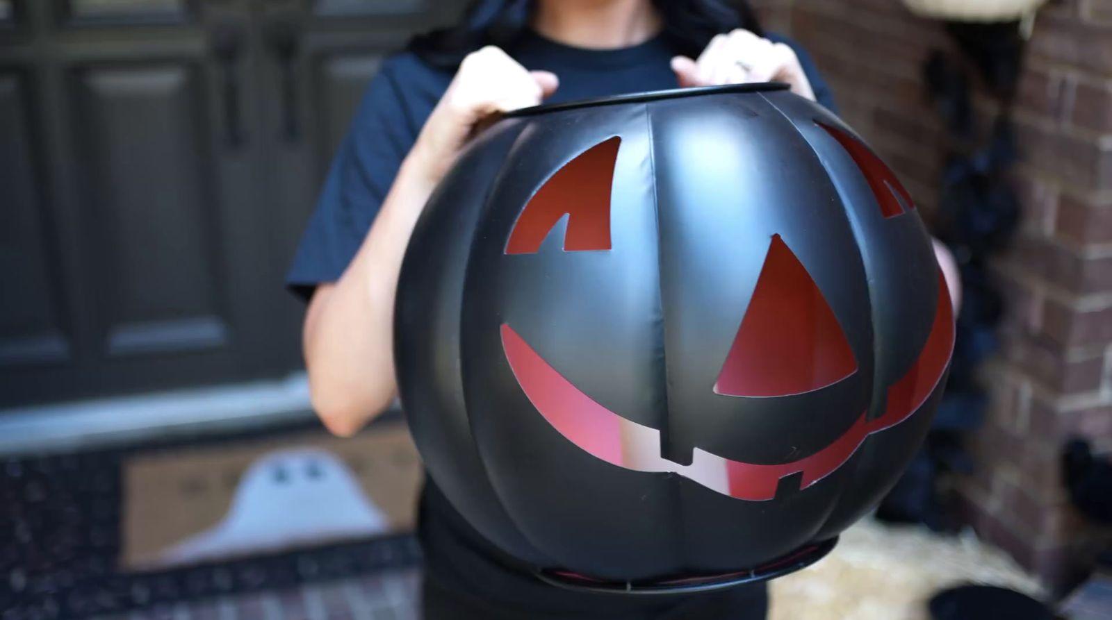 a person holding a pumpkin shaped helmet in front of a door