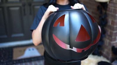a person holding a pumpkin shaped helmet in front of a door