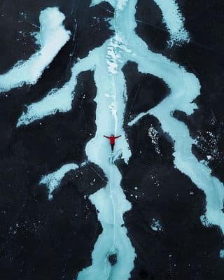 an aerial view of a person walking across a river