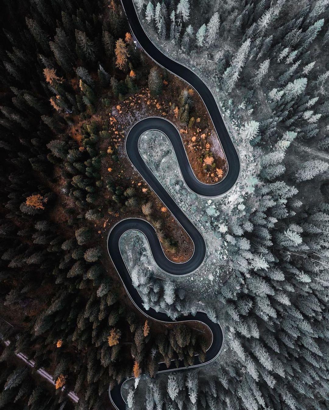 an aerial view of a winding road surrounded by trees