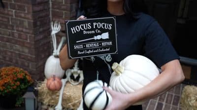 a woman holding a sign that says hoccus pocus