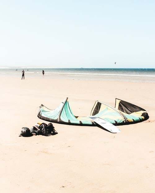a kite laying on the beach with people in the background