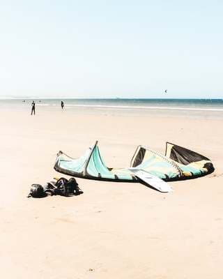 a kite laying on the beach with people in the background