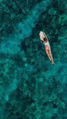 a woman in a bikini on a surfboard in the ocean