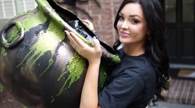 a woman is holding a large green vase