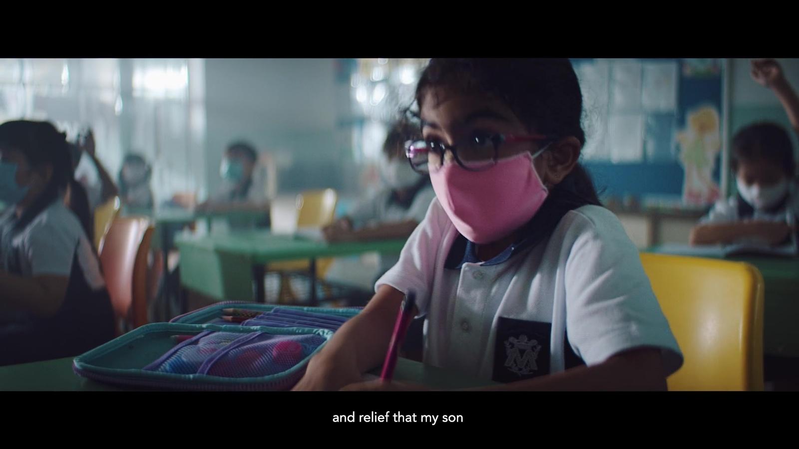 a young girl wearing a pink mask while sitting at a table