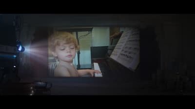 a young boy playing a piano in a dark room