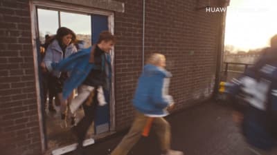 a group of people walking past a brick building