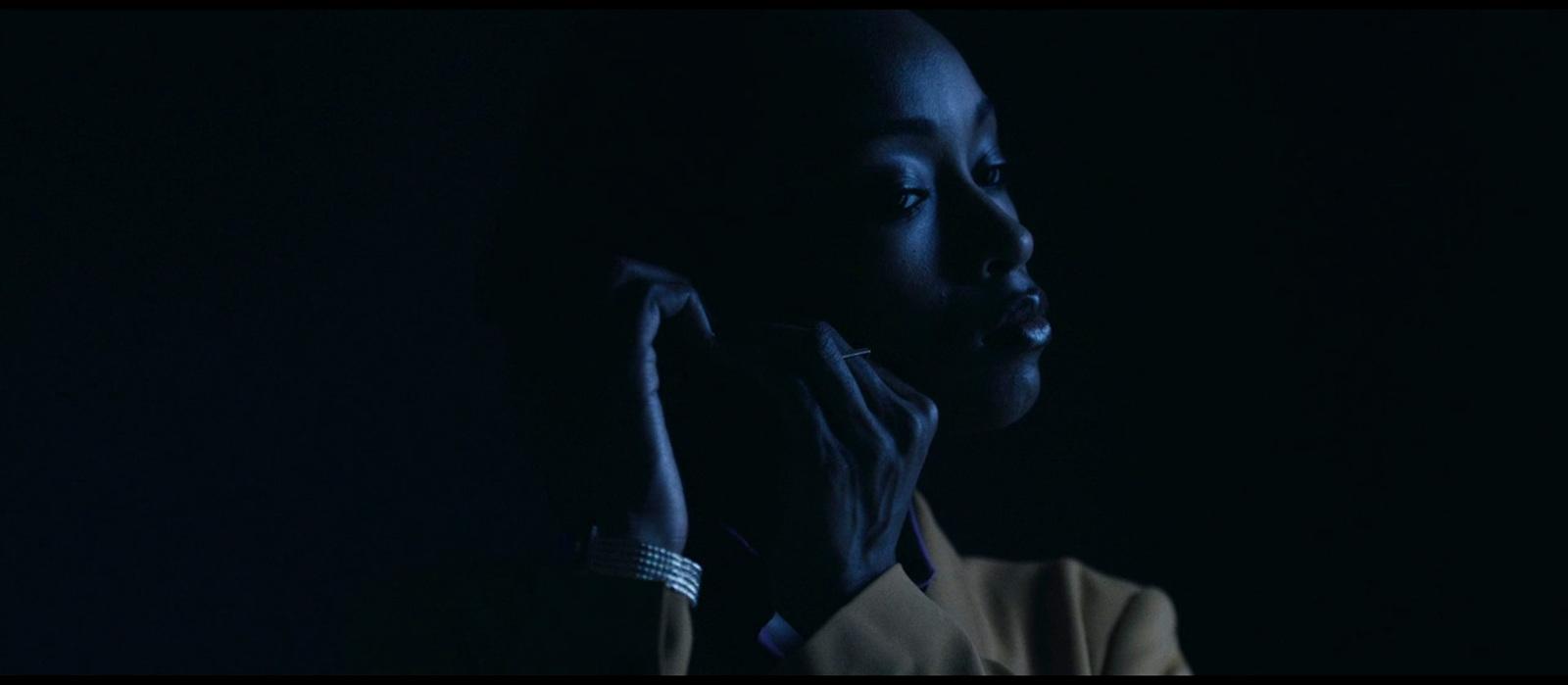 a woman in a dark room holding her hand up to her face