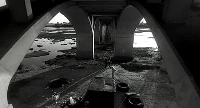 a black and white photo of a bridge over water