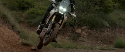 a man riding a motorcycle down a dirt road