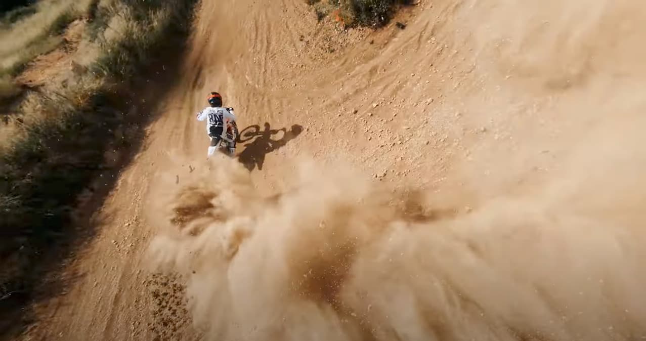 a man riding a dirt bike down a dirt road