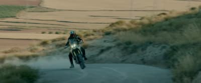 a man riding a motorcycle down a dirt road