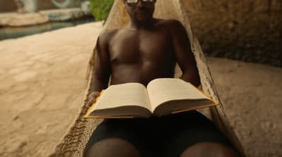 a man sitting on a bench reading a book