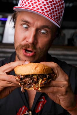 a man in a red and white hat is holding a sandwich