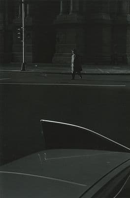 a black and white photo of a man walking down a street