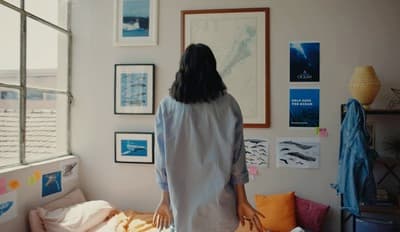 a woman standing in a bedroom looking out a window