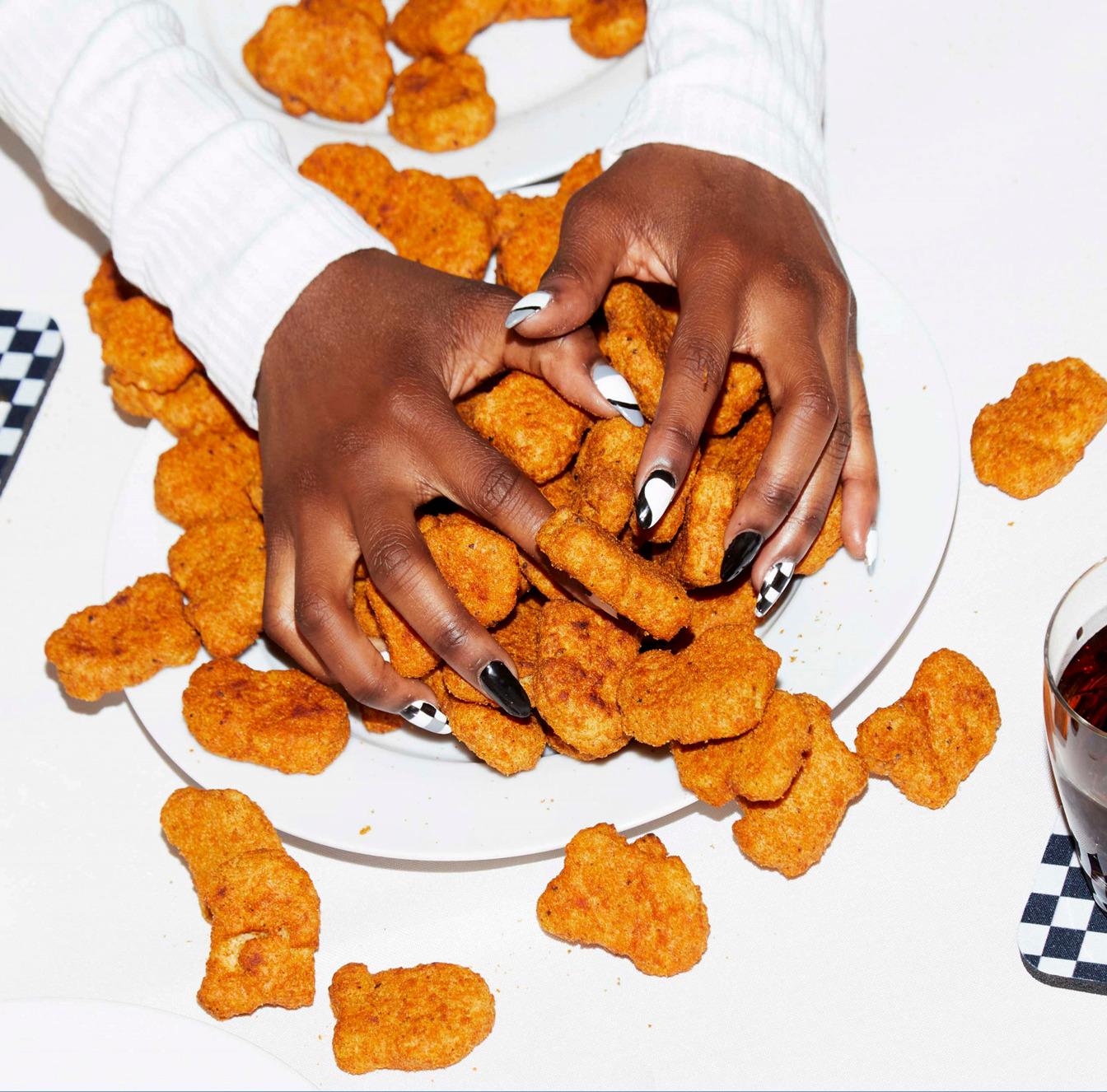 a woman holding a plate of chicken nuggies