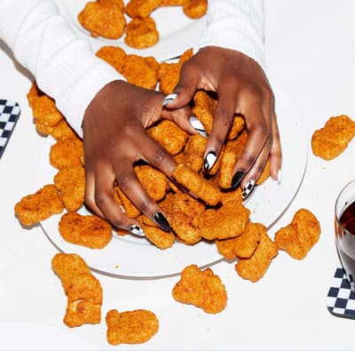 a woman holding a plate of chicken nuggies