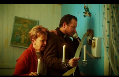 a man and a woman holding candles in a room