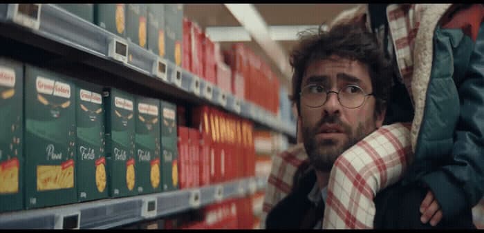 a man with glasses standing next to a shelf of books