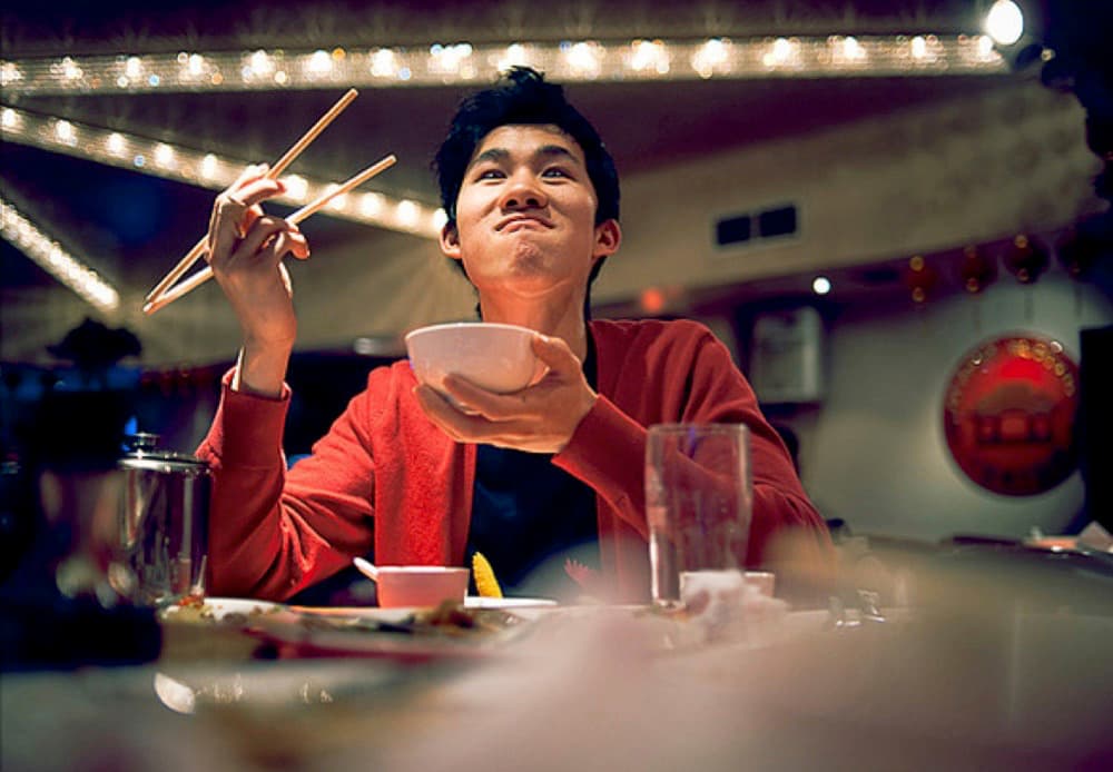 a man sitting at a table with chopsticks in his hand