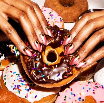 a close up of a person holding a doughnut with sprinkles