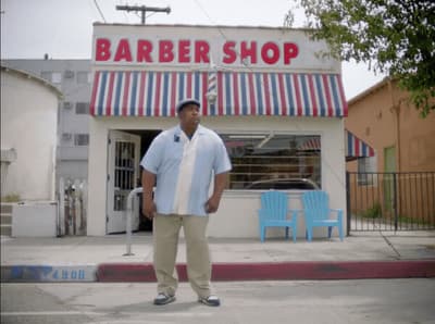 a man standing in front of a barber shop