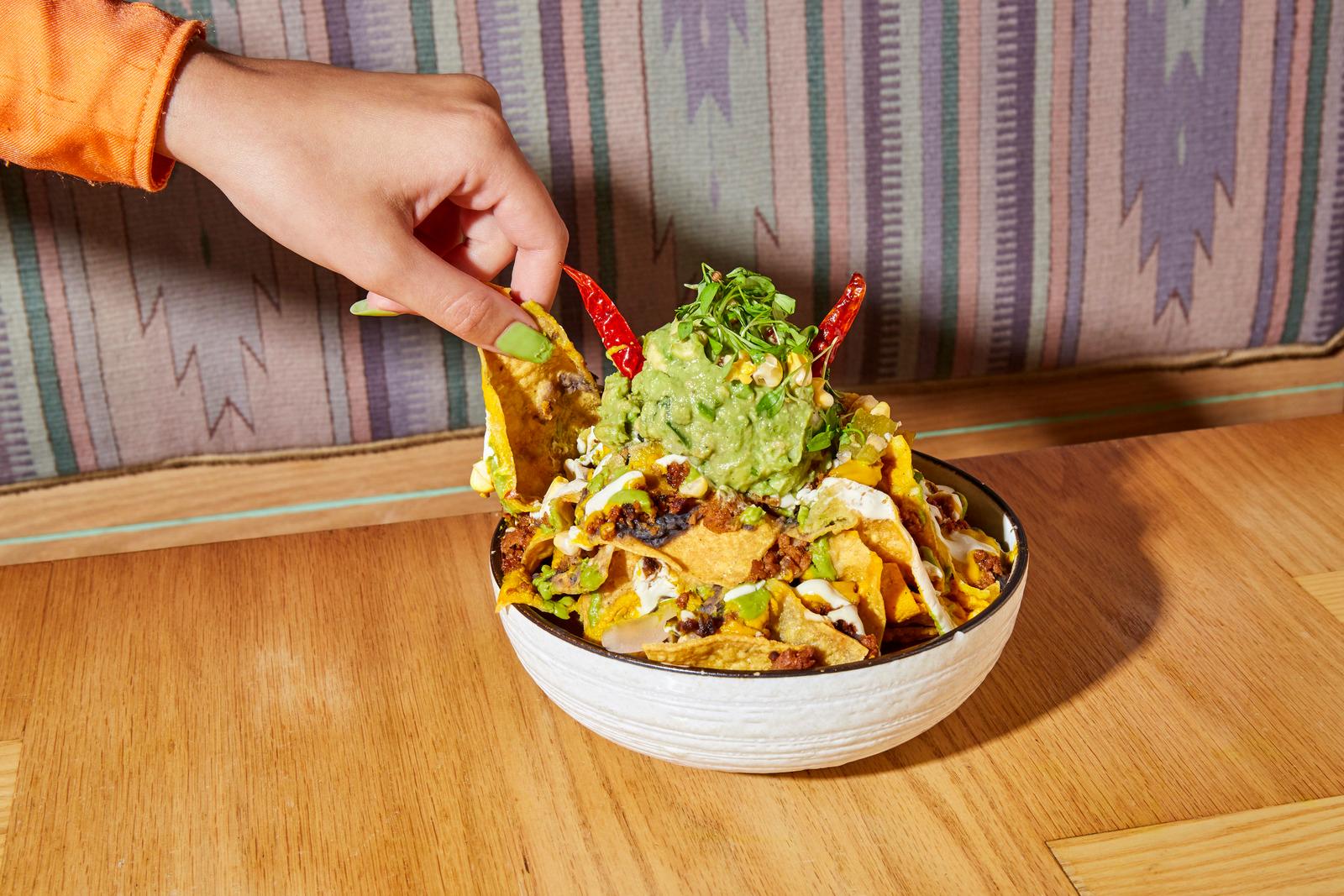 a person dipping a tortilla into a bowl of guacamole