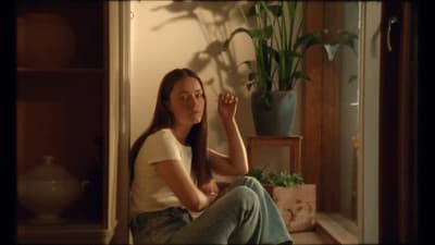 a woman sitting on the floor in front of a potted plant