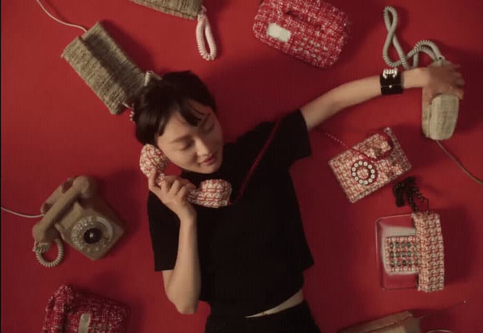 a woman laying on the ground surrounded by purses and cell phones