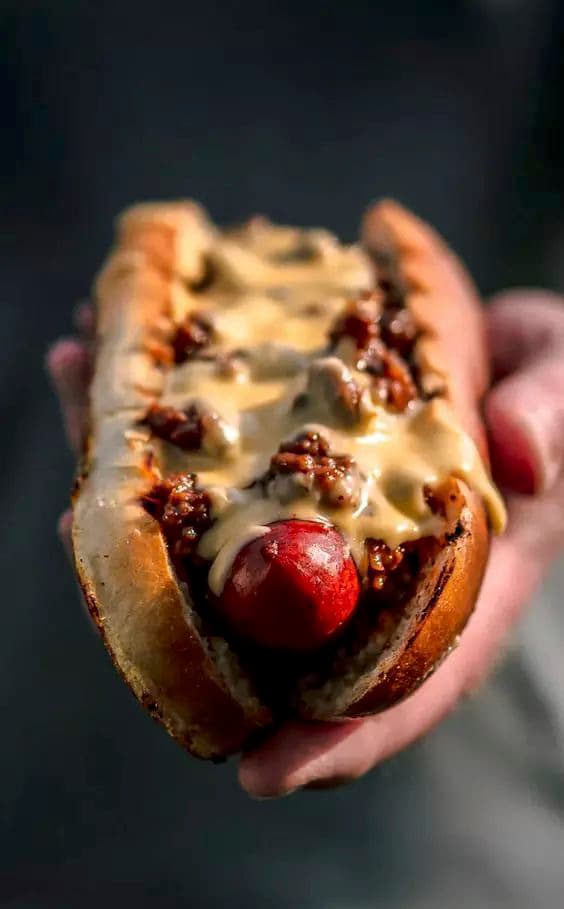 a person holding a hot dog in their hand