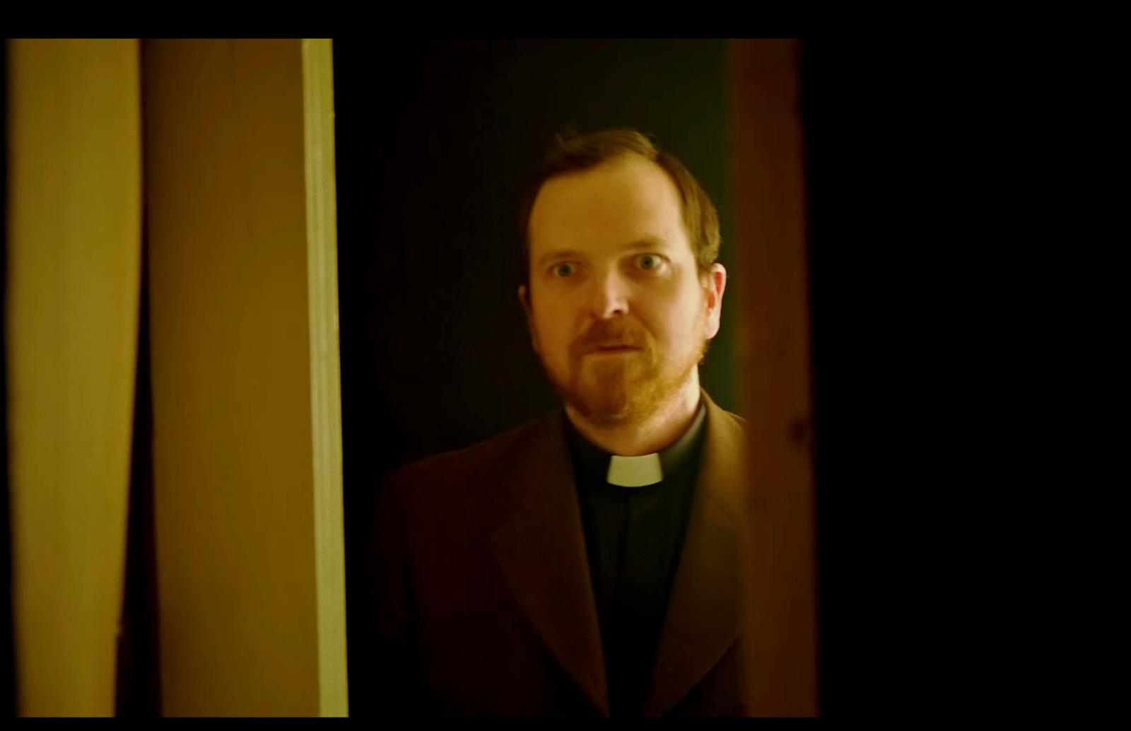 a man in a priest's outfit standing in a doorway