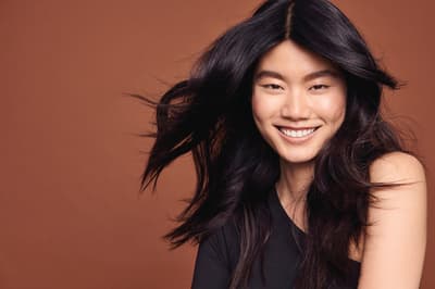 a woman with long black hair is smiling