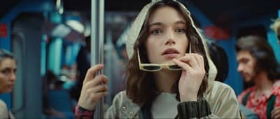 a woman in a hooded jacket eating food on a train