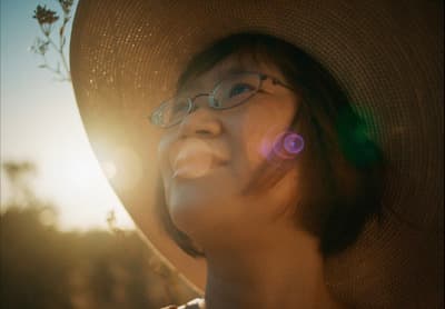 a woman wearing a hat and glasses is smiling